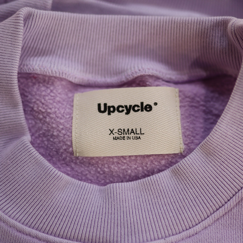 Cream t shirt woven labels on a purple garment.