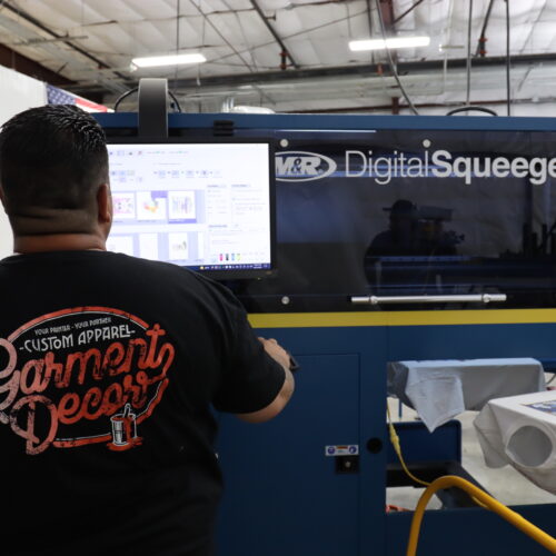 This is a photo of Garment Decor's digital screen printing machine with an employee operating it.