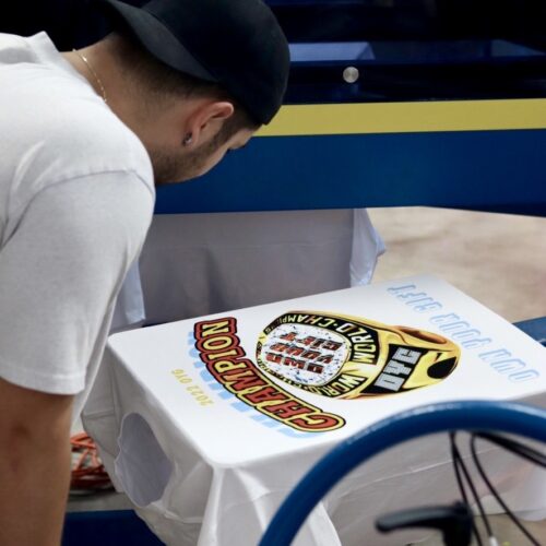 This is a photo of Garment Decor's digital squeegee and an employee looking at the digital screen print for quality control.