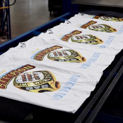 This is a photo of Garment Decor's Digital Squeegee printed t-shirts coming out of the drying conveyer belt.