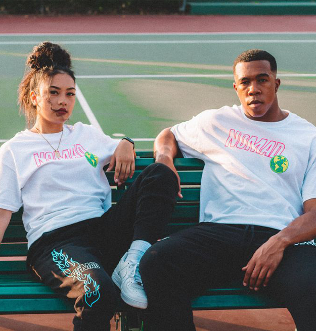 Two people sitting on a bench wearing matching white t-shirts with the word "normal" printed on them.
