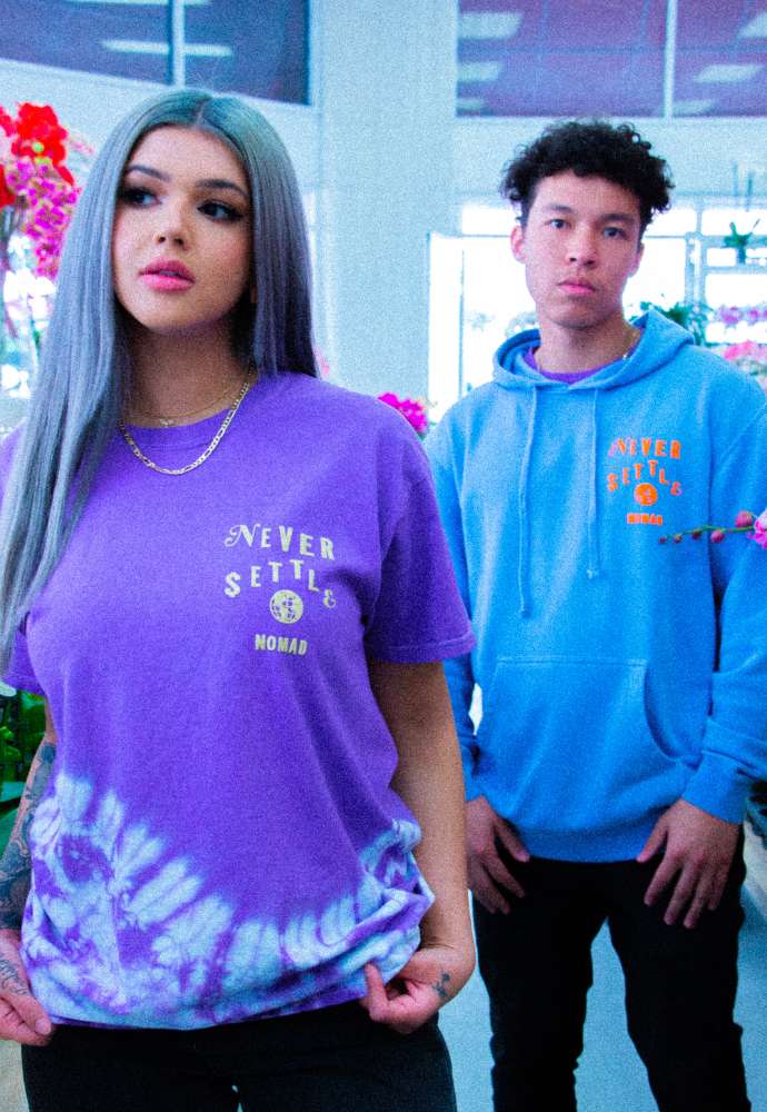 Two young adults wearing hoodies with the text "never settle" standing indoors.