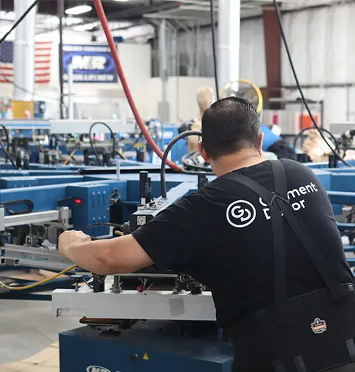 A photo of a Garment Decor employee on the screen printing machine preparing a custom t-shirt order.