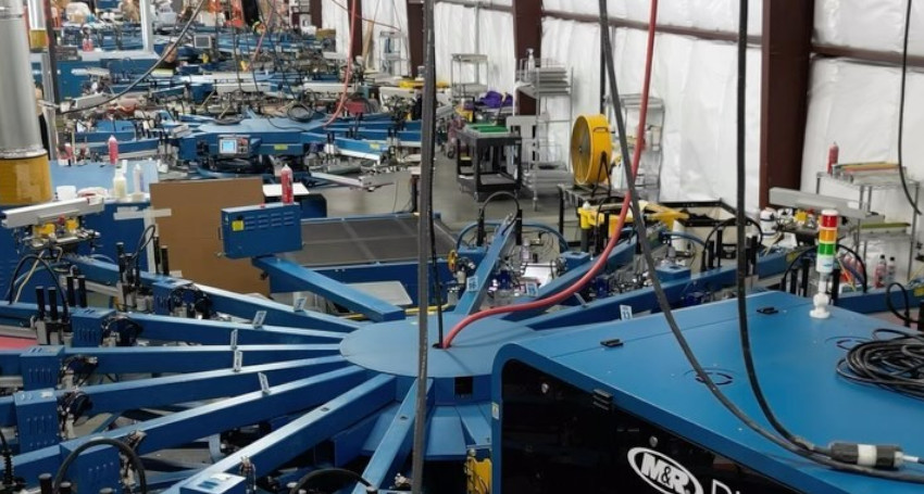 Interior of a busy industrial factory with multiple machines, including a prominent blue carousel in the foreground.