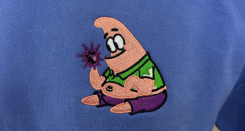 Embroidered patch of Patrick Star from SpongeBob SquarePants, discovering types of print, holding a purple flower, on a blue fabric.