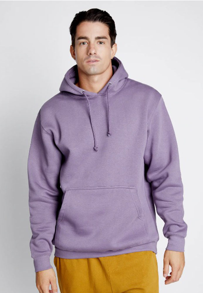 Man wearing a purple hoodie and mustard pants, standing with a neutral expression and looking at the camera.