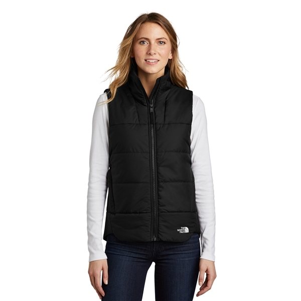 A woman with long hair is wearing a black Women's The North Face Vest over a white long-sleeve shirt and blue jeans, standing against a plain white background.