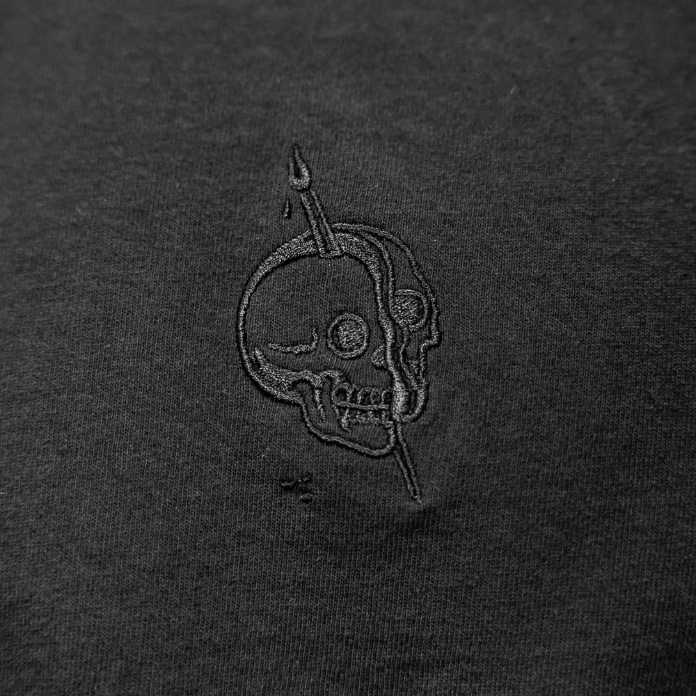 Custom embroidered tonal design in black thread on a black t-shirt.