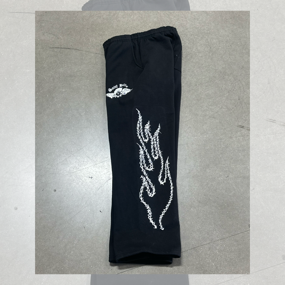 This is a photo of custom screen printed black joggers with white plastisol ink on the side and on the left pocket for our clothing brand customer.