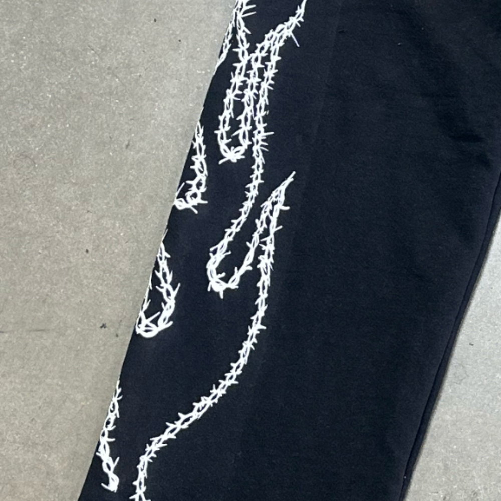 This is a zoomed in photo of custom screen printed black joggers with white plastisol ink on the side for our clothing brand customer.