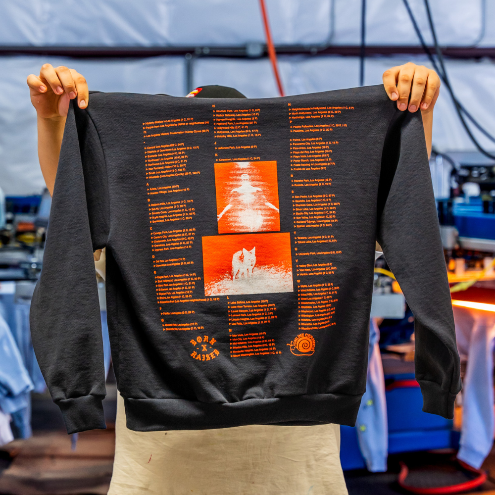 Displayed is the back view of a pigment black Independent Trading IND420XD Mainstreet 420gm Heavyweight Pullover Hoodie, adorned with a large and vibrant custom screen print of Born Online design printed by Garment Decor, ideal for bold streetwear branding