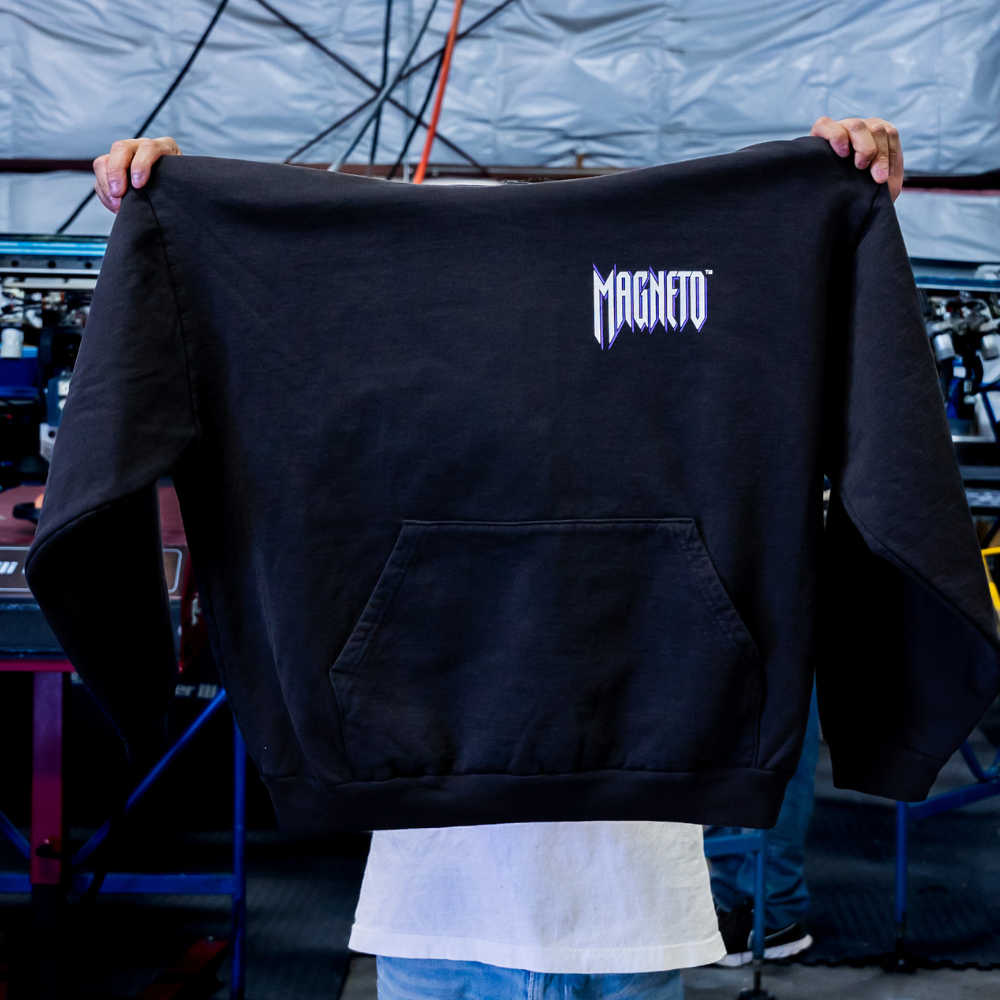 A man holding the Front view of a Los Angeles Apparel HF09 Heavy Fleece Hoodie showcasing custom screen printing Magneto design.