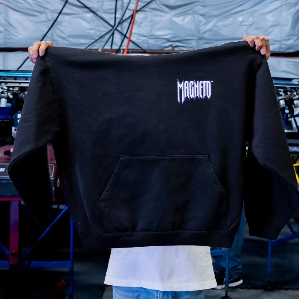 A man holding the front view of the black Los Angeles Apparel HF-09 L/S HEAVY FLEECE HOOD PO 14 OZ with a vibrant custom screen print design printed by Garment Decor