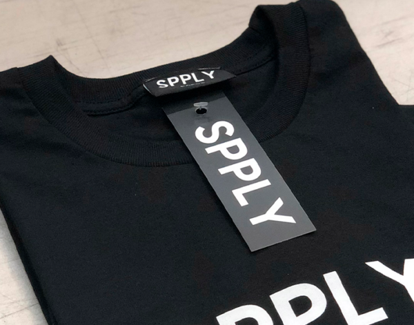 This is a photo of a black t-shirt with a black hang tag for a clothing brand